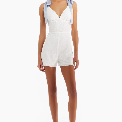 Girl in white romper with blue straps, front facing.